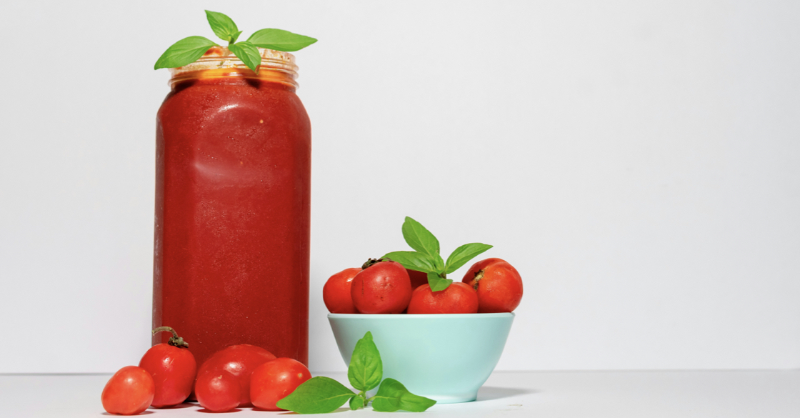 Nell'immagine sono raffigurati un barattolo di passata di pomodoro, del basilico e una ciotola con dentro dei pomodorini
