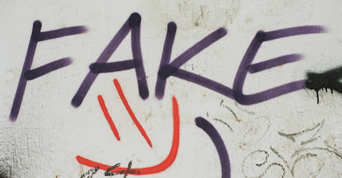 L'immagine raffigura un graffito con la scritta fake e uno smile