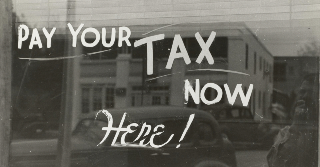 L'immagine rappresenta una scritta sul vetro "Pay your tax now here"
